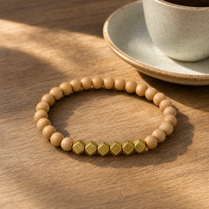 The Rosewood 6mm Bead Bracelet with Gold Accents on a sunlit wooden cafe table beside a ceramic coffee cup