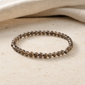 Soultheory Smoky Quartz 4mm Round Bead Bracelet on a travertine slab and linen