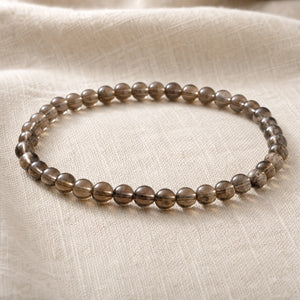 Close-up of the Smoky Quartz 4mm Round Bead Bracelet on natural linen