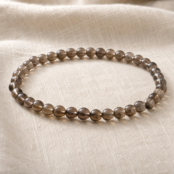 Close-up of the Smoky Quartz 4mm Round Bead Bracelet on natural linen