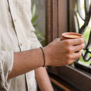 Man wearing the Smoky Quartz bracelet, holding a cup of chai