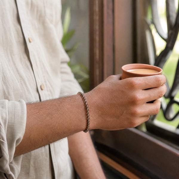 Man wearing the Smoky Quartz bracelet, holding a cup of chai