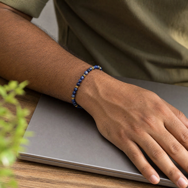 Man wearing the Sodalite bracelet, at a wooden desk