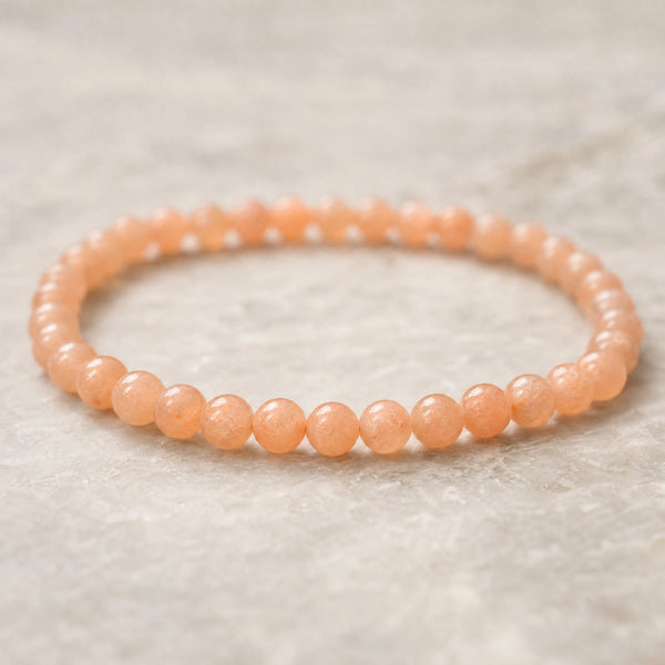Close-up of the Sunstone 4mm Round Bead Bracelet on a pale stone surface