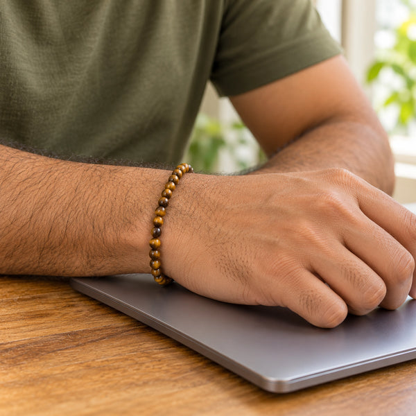 Man wearing the Tiger Eye bracelet, at a wooden desk