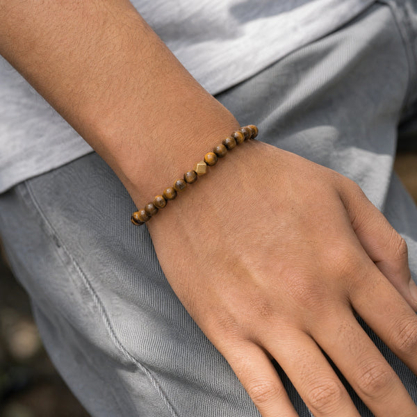 Man wearing the Tiger Eye 6mm Bead Bracelet with Gold Accent with a grey t-shirt