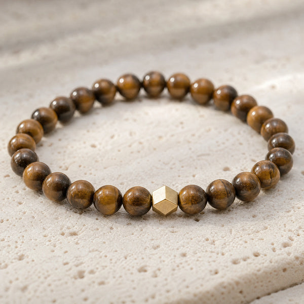 Close-up of the Tiger Eye 6mm Bead Bracelet with Gold Accent on pale travertine