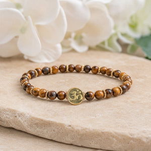 Soultheory Tiger Eye 4mm bracelet with gold-tone spacers and the Om charm on a stone slab