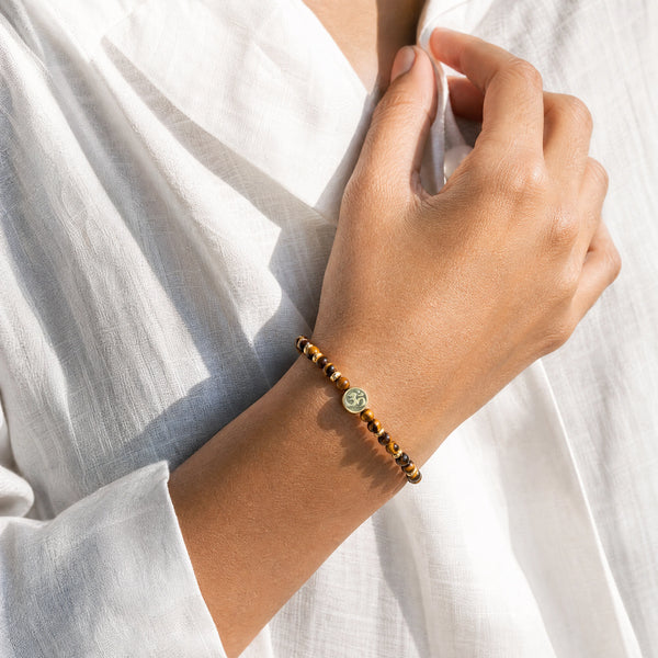 Woman wearing the Tiger Eye 4mm bracelet with Om charm and a white linen shirt