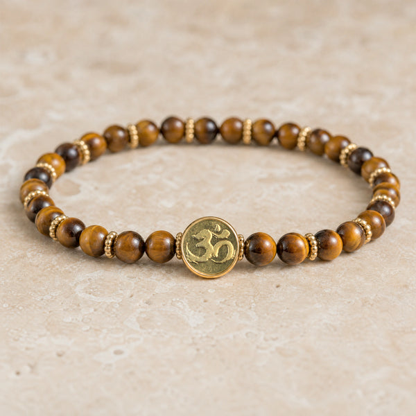 Tiger Eye 4mm bracelet with the Soultheory Om charm and gold spacers on travertine