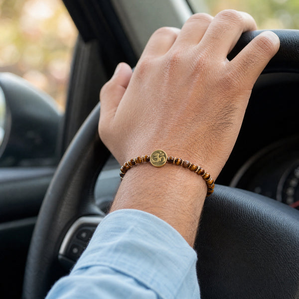 Man wearing the Tiger Eye Om charm bracelet while driving