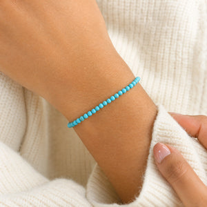 Woman wearing the Turquoise 4mm Round Bead Bracelet with a cream knit cardigan