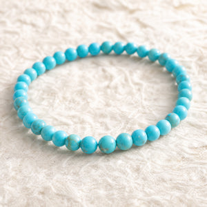 Close-up of the Turquoise 4mm Round Bead Bracelet on cream handmade paper