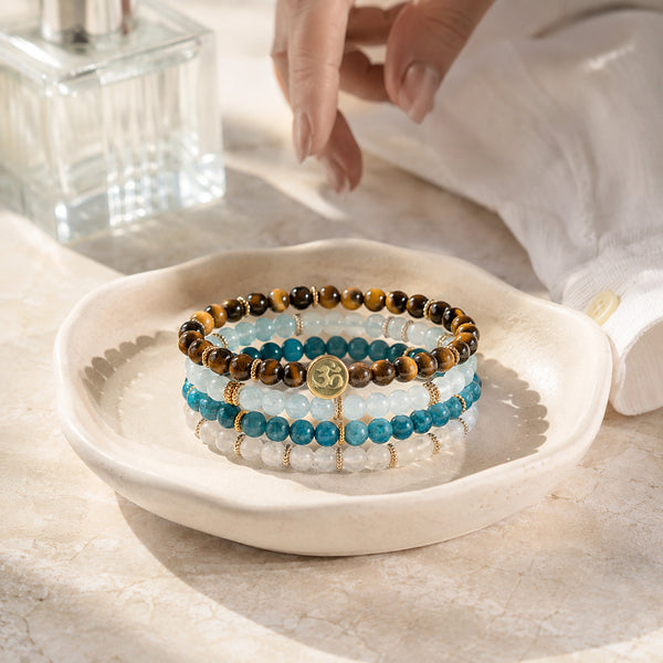 Abundance option A2: four gemstone bracelets in an ivory jewellery dish during a morning dressing-table routine