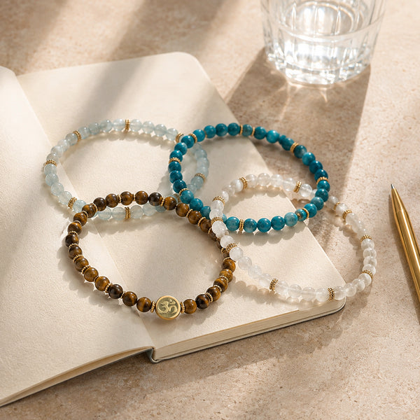 Abundance option A4: the four complete crystal bracelets on an open journal in morning sunlight