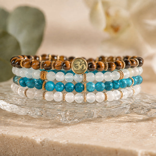 Abundance Tiger's Eye, Aquamarine, Apatite and Moonstone bracelet stack with Soultheory's photographed gold charm on glass and ivory stone