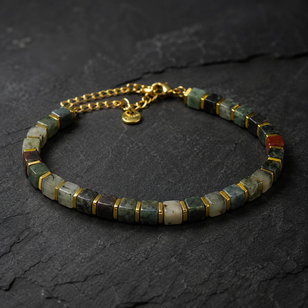 African bloodstone bracelet with golden hematite spacers displayed on dark slate stone - Soultheory