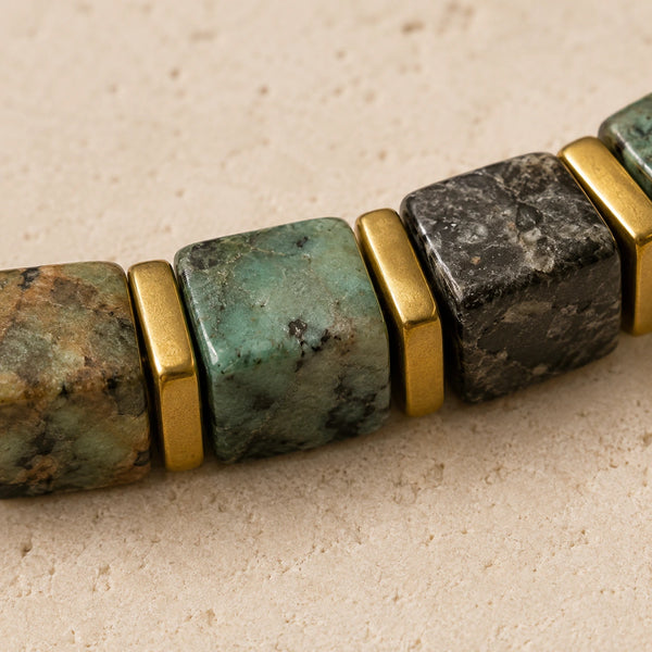 Close-up of African turquoise cube beads showing green and black matrix with gold spacers
