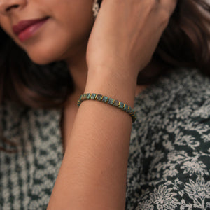 African turquoise bracelet with golden hematite worn on a woman's wrist with a floral dress