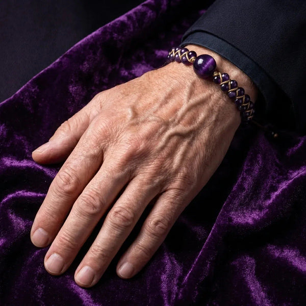 Purple amethyst cord bracelet on a man's hand resting on deep purple velvet