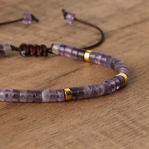 Close-up of purple amethyst bracelet beads with gold spacer accents on wood surface