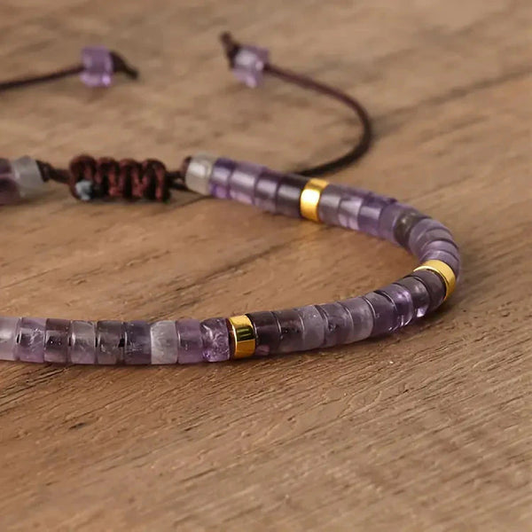 Close-up of purple amethyst bracelet beads with gold spacer accents on wood surface