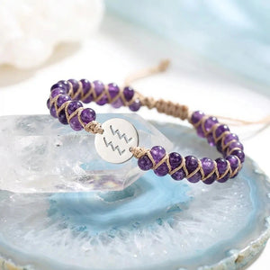 Amethyst Aquarius zodiac bracelet styled on a clear quartz crystal, purple beads with tan cord