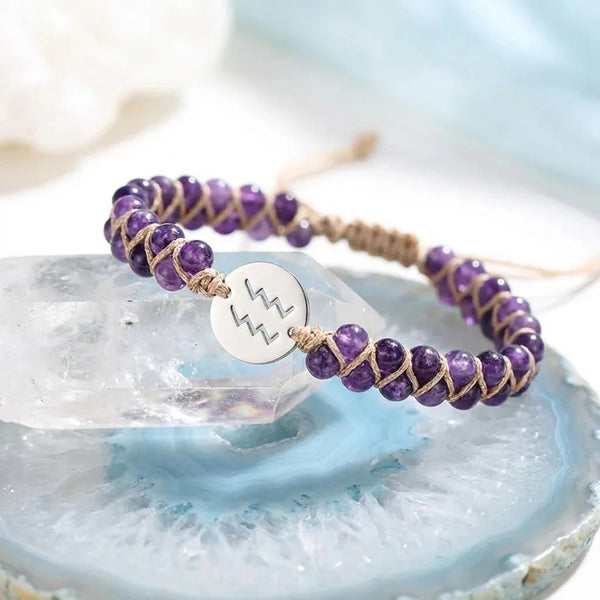 Amethyst Aquarius zodiac bracelet styled on a clear quartz crystal, purple beads with tan cord