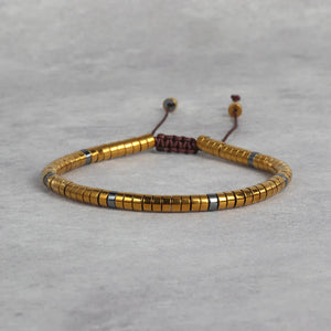 Gold hematite bracelet with grey spacer beads and adjustable cord for wealth and success