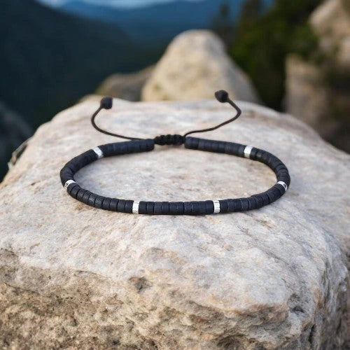 Black onyx flat-bead bracelet resting on a rock for grounding and protection