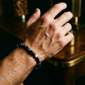 Black onyx stainless steel bracelet on a man's wrist in warm lamplight, confident everyday look