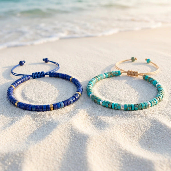 Matching navy lapis lazuli and turquoise imperial jasper bracelet pair resting on beach sand