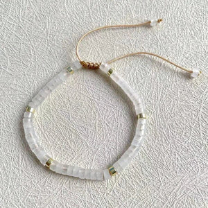 Flat-lay of the clear quartz beaded bracelet with adjustable cord on a textured white surface