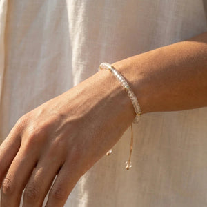 Clear quartz 4mm bracelet worn on a wrist in soft sunlight, adjustable cord for clarity and focus