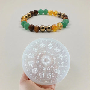 Dhan Yog money magnet bracelet shown with a zodiac selenite recharging plate