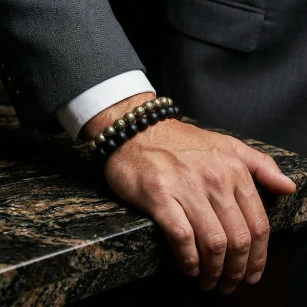 Karungali ebony and golden pyrite bracelet stack worn on a man's wrist with a formal suit
