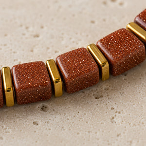 Close-up of shimmering goldstone cube beads with gold spacers showing copper glitter texture