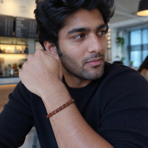 Goldstone bracelet with golden hematite worn on the wrist by a man at a cafe