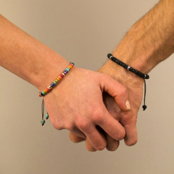 Couple holding hands wearing matching lava rock and rainbow 7 chakra bracelets for grounding