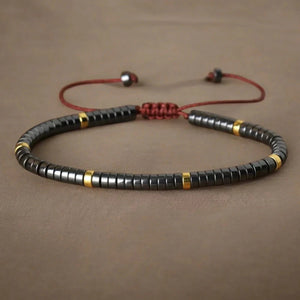 Hematite heishi bead bracelet with gold accents and red adjustable cord for protection