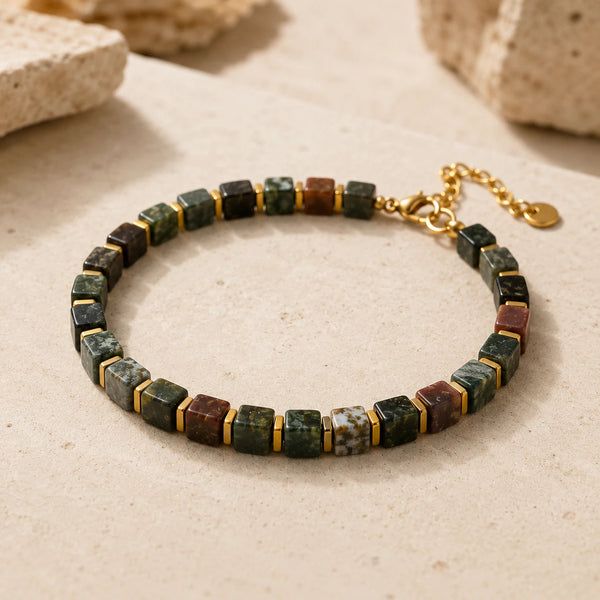 Indian agate bracelet with golden hematite spacers arranged on a light stone surface