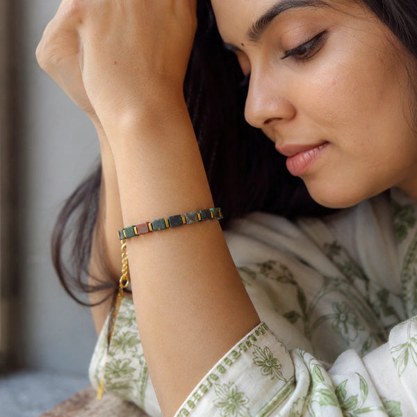 Indian agate bracelet with golden hematite worn on wrist by a woman in a green floral outfit