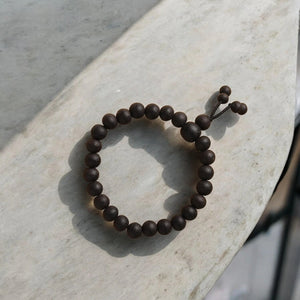 Karungali ebony wood bracelet with matte dark beads on adjustable cord, front view