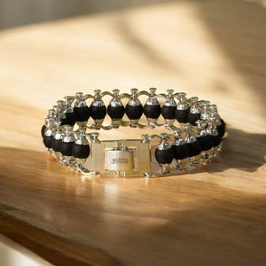 Angle view of black ebony karungali beads and silver plated links resting on a wooden surface