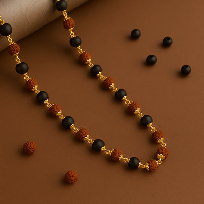 Karungali and rudraksha mala necklace with gold caps draped on a warm brown backdrop - Soultheory India