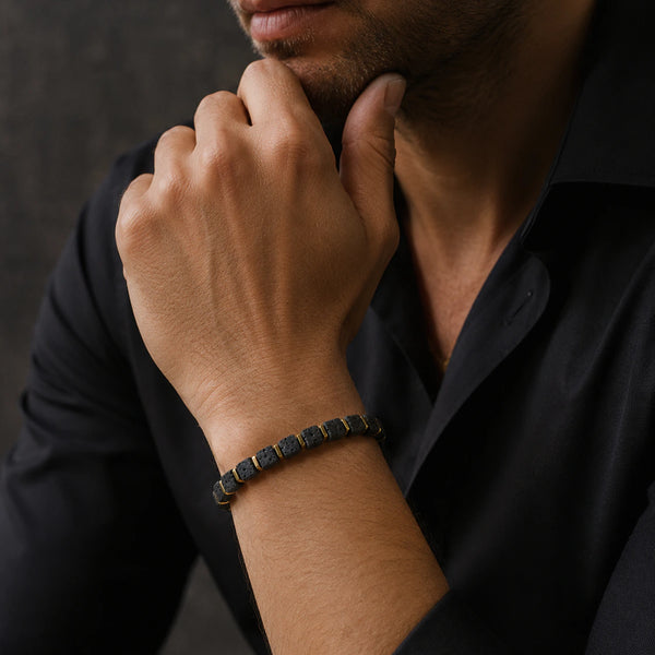 Lava stone bracelet with golden hematite worn on a man's wrist as he rests his chin on his hand