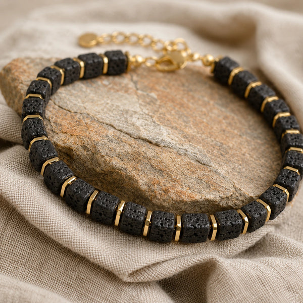 Lava stone bracelet draped over a natural stone with linen showing black porous lava beads