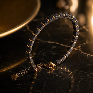 Lava stone bracelet with gold spacers on dark marble in warm golden light - Soultheory
