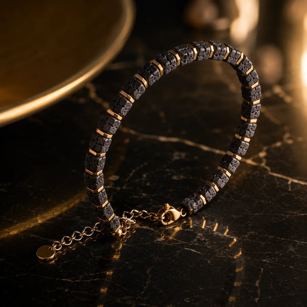 Lava stone bracelet with gold spacers on dark marble in warm golden light - Soultheory