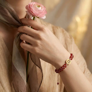 Red agate Libra zodiac bracelet worn on a woman's wrist as she holds a pink flower, gold sign charm on top